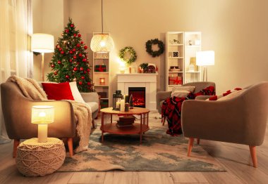 Işıl ışıl Noel ağacı, lambalar ve mumlarla dolu karanlık oturma odasının içi