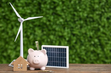 Rüzgar türbini modeli, kumbara, ev figürü ve açık havada taşınabilir güneş paneli. Yeşil Enerji kavramı