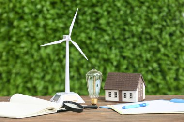 Rüzgar türbini, ev modeli, ampul ve açık havada kitap. Yeşil Enerji kavramı