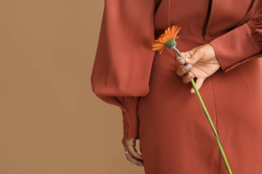 Manikürlü genç bir kadın elinde Gerbera çiçeğini tutuyor.