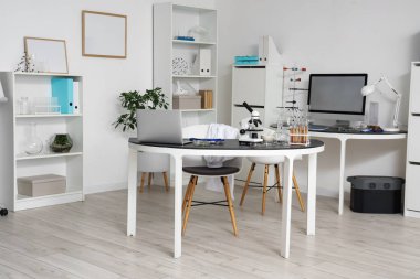 Sıraları ve kimyasal cam takımları olan bir laboratuvar.