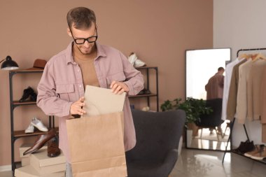 Genç adam ayakkabı kutusunu mağazadaki alışveriş çantasına koyuyor.