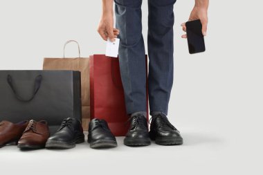 Yeni ayakkabılı, kredi kartı ve cep telefonlu bir işadamı.