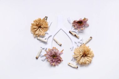 Sigara izmaritli kağıt ciğerler ve beyaz arka planda kurumuş çiçekler.