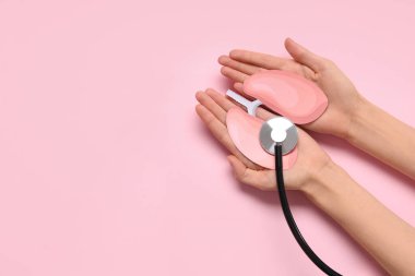 Kağıt ciğerli kadın eller ve pembe arka planda steteskop.