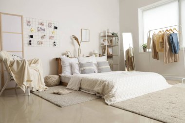 Işıl ışıl yatak odasının içinde, duvarında rahat bir yatak ve ruh hali tahtası asılı.