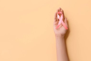 Kadın eli ve arka planda pembe kurdele, yakın plan. Göğüs kanseri farkındalığı konsepti