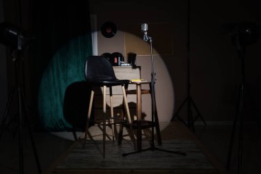 Karanlık odada tabure, masa ve mikrofonun olduğu stand-up sahnesinin görüntüsü