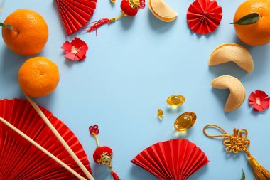 Mavi arka planda Çin sembolleri, mandalinalar ve fal kurabiyelerinden yapılmış bir çerçeve. Yeni yıl kutlaması