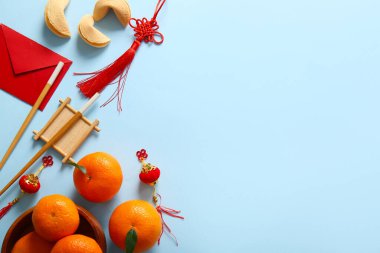 Şans kurabiyeli mandalinalar, kırmızı zarflar ve mavi arka planda Çince semboller. Yeni yıl kutlaması