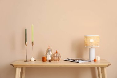 Balkabağı şeklinde mumlar, parlak lamba ve bej duvarın yanındaki bankta süslemeler.