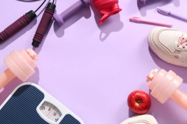 Elma, spor ayakkabısı ve eflatun arkaplanlı spor malzemelerinden yapılmış çerçeveler. Kilo verme konsepti