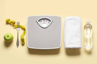 Ölçüm bandı, elma ve bej arka planda bir şişe su ile ölçeklendirilir. Kilo verme konsepti