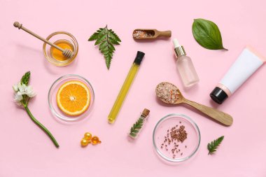 Doğal kozmetik ürünlerini pembe arka planda hazırlamak için numune ve malzemelerle dolu şişeler.