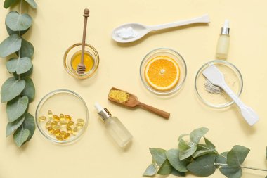Sarı arka planda doğal kozmetik ürünlerini hazırlamak için numune ve malzemelerle dolu yağ şişeleri, petri kapları.