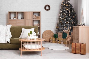 Oturma odasının içinde kanepe, Noel ağacı ve yanan mumlar var.