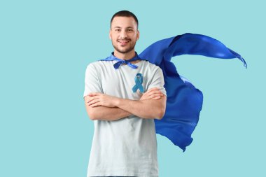 Arka planda mavi kurdeleli süper kahraman pelerinli genç adam. Prostat kanseri farkındalığı