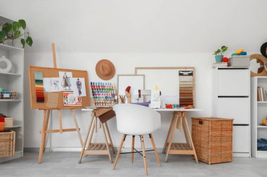 Moda tasarımcısının stüdyosunun içinde iş yeri ve çizimler var.