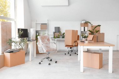 Taşınma gününde koltuklar ve karton kutularla dolu masalar