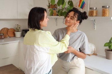 Genç lezbiyen çift mutfakta gülümsüyor.