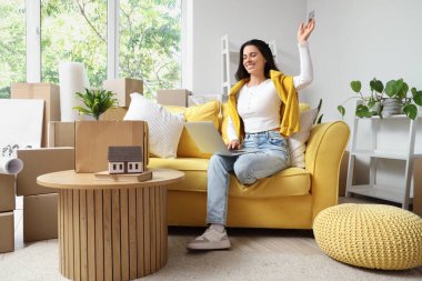 Taşınırken odada dizüstü bilgisayar kullanan kredi kartı olan güzel bir kadın.