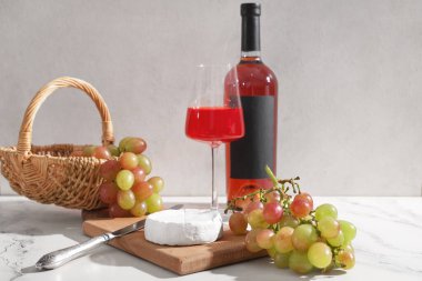 Tahta tahta tahta, olgun üzümler, peynirli camembert peyniri ve beyaz arka planda bir bardak şarap.