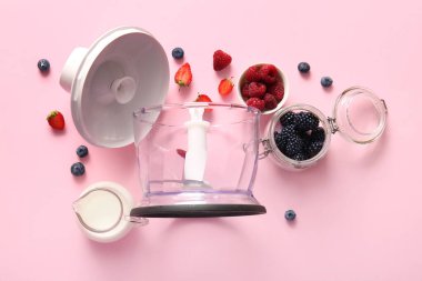 Modern blender with jug of milk and berries on pink background clipart