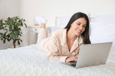 Güzel bir kadının yatak odasında dizüstü bilgisayar kullandığı bir sabah.