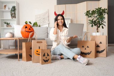 Şeytan boynuzları içinde genç bir kadın Cadılar Bayramı için internette alışveriş yapıyor.