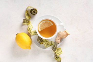 Bir fincan diyet çay, limon, zencefil kökü ve arka planda şerit. Kilo verme konsepti