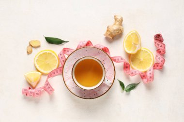 Bir fincan diyet çay, limon, zencefil kökü ve arka planda şerit ile kompozisyon. Kilo verme konsepti
