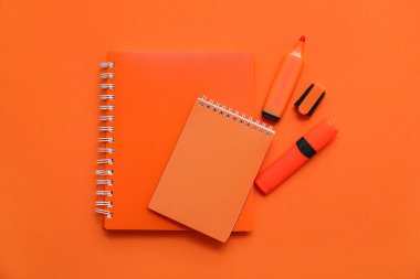 Turuncu arkaplanda defterler ve işaretleyiciler