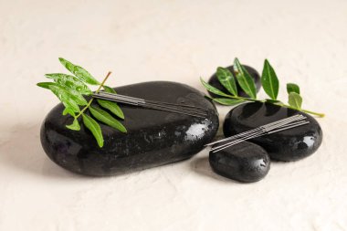 Açık arkaplanda akupunktur iğneleri ve spa taşları