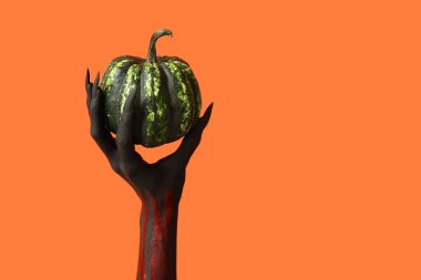 Pençeleri ve turuncu arka planda yeşil balkabağı olan kara cadı eli. Cadılar Bayramı