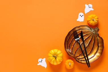 Kâğıt hayaletler ve turuncu arka planda balkabağıyla Cadılar Bayramı kutlaması için şenlik masası.