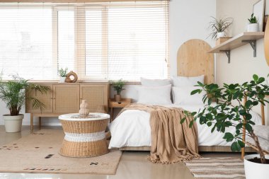 Yatak, kahve masası, ev bitkileri ve yatak odasının iç tarafındaki çekmeceler.