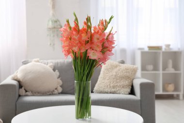 Aydınlık oturma odasındaki masada üzerinde gladiolus çiçekleri olan vazo, yakın plan.