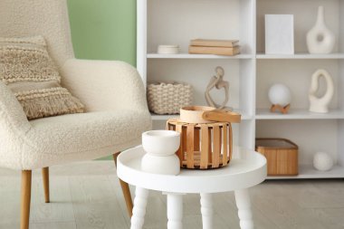 İçinde vazo ve fener olan sehpa yeşil duvarın yanında.