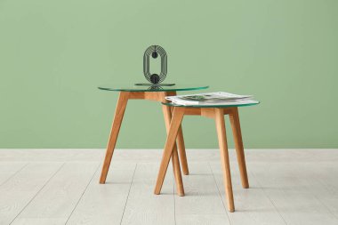 Dekorlu kahve masaları ve yeşil duvarın yanındaki dergiler.