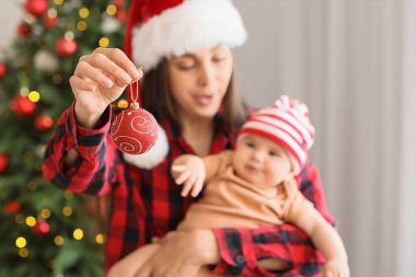 Küçük bebeği ve Noel balosuyla Noel Baba şapkalı mutlu anne, yakın plan.