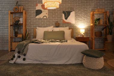 Yatak odasının içinde yatak odası, raf üniteleri, komodin ve parlayan lamba.