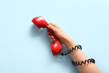Mavi arka planda telefon ahizesi olan bir kadın. Dedikodu konsepti
