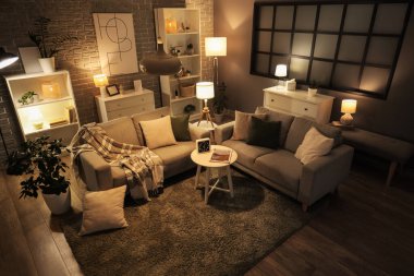 Sıcak kanepeler, sehpa ve oturma odasının içinde parlayan lambalar.