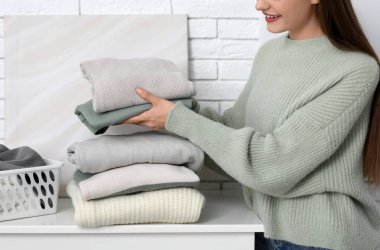 Evde klozette sıcak süveter yığını olan genç bir kadın.