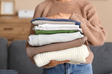 Evde bir yığın elbisesi olan genç bir kadın, yakın plan.