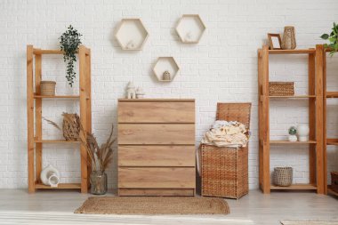 Çamaşır sepetli, ahşap şifoniyerli ve raflı çamaşır odasının içi.