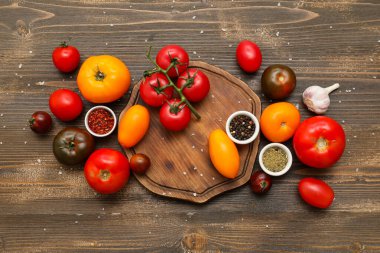 Taze olgun domatesler, sarımsak ve ahşap zemin üzerinde farklı baharatlar.