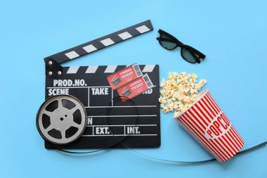 Patlamış mısırlı film alkışları, sinema biletleri ve mavi arka planda film makarası.