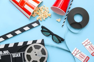 Patlamış mısırlı, sinema biletli, gözlüklü ve mavi arka planda film makaralı alkış.
