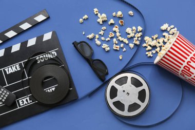 Mavi arka planda gözlüklü, patlamış mısırlı ve film makaralı bir film.